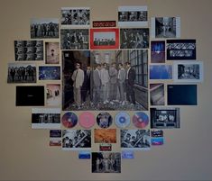 a group of men standing next to each other in front of a wall covered with pictures