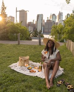 a woman is sitting on the grass eating and drinking