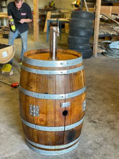 a man standing next to a wooden barrel