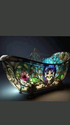 an ornate glass bathtub with flowers on the bottom and sides is illuminated by a dim light