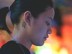 a woman with a tattoo on her neck looking at her cell phone in the dark