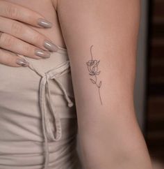 a woman's arm with a single rose tattoo on the left side of her arm