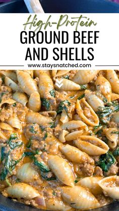 a skillet full of ground beef and shells with spinach on top, in a blue pan