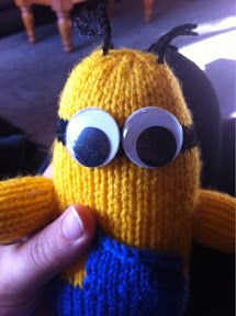 a hand holding a knitted toy with googly eyes