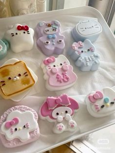 there are many hello kitty shaped cookies on the tray, all decorated in pastel colors