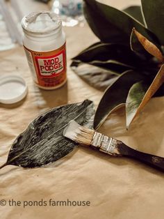 a paintbrush sitting on top of a table next to a leaf and some glue