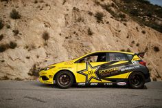 a yellow sports car parked in front of a rocky mountain side with a star painted on it's side