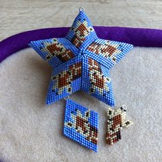 a cross stitch star ornament and two pieces of bead work on a purple pillow