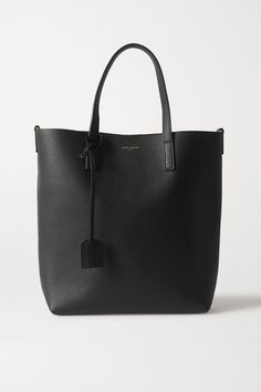 SAINT LAURENT's tote will hold your essentials and a little extra, making it ideal for carrying on busy days. Crafted in Italy from buttery black leather, it's minimally detailed with the brand's signature tag and gold-tone lettering. The sturdy top handles are sized to fit comfortably on your shoulder or the crook of your arm. Wear it with: SAINT LAURENT Tank, SAINT LAURENT Shorts, SAINT LAURENT Sandals. -- Black leather (Calf) - Snap-fastening tab at open top - Comes with dust bag - Imported Saint Laurent Black Tote Bag, Saint Laurent Work Bag, Saint Laurent Sandals, Saint Laurent Tote, Arm Wear, Street Style Bags, Black Leather Tote, North South, Saint Laurent Bag