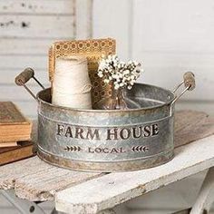 an old metal tub with yarn and scissors in it sitting on a table next to some books