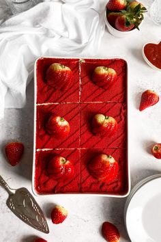 strawberries are arranged in squares on top of a white table with spoons and bowls