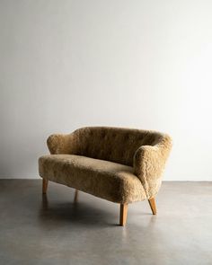 a couch sitting on top of a cement floor next to a white wall in an empty room