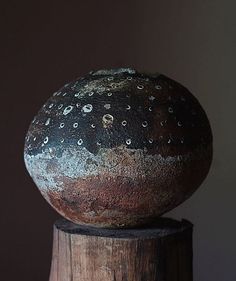 an old ball sitting on top of a wooden post in front of a dark wall