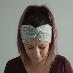 a woman wearing a knitted headband with a knot in the middle and her eyes closed