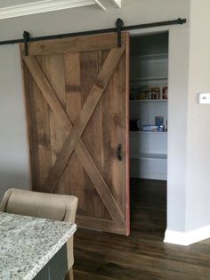 an open barn door in a kitchen with marble counter tops and wooden flooring on the side