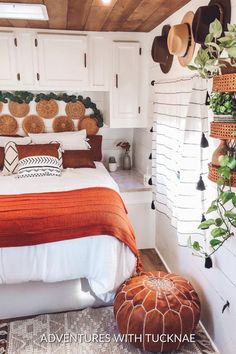 a bedroom with white walls and wooden ceilinging has a bed covered in an orange blanket