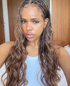 a woman with long braids on her head and wearing a blue tank top is looking at the camera