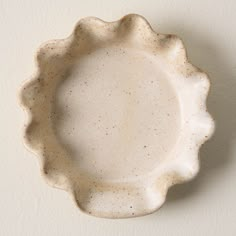 a white plate with speckles on it is hanging from the wall in an empty room