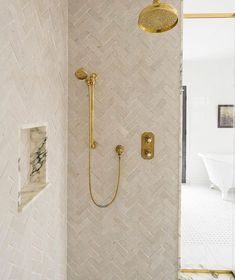 a bathroom with a shower head, hand held shower faucet and marble tile walls