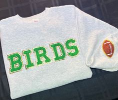 Philadelphia Eagles Gear! BIRDS patch letters iron on and stitched on for extra support on an over sized crewneck. Green letters with a Gold Glitter Trim. Brown Football patch on the sleeve. Patch Work Shirt, Football Eagles, Crafts 2024, Patch Letters, Philadelphia Eagles Shirts, Eagles Sweatshirt, Philadelphia Eagles Gear, Eagles Shirt, Eagles Gear