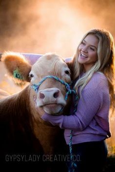 a woman is hugging a cow in a field