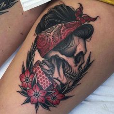 a woman's thigh with a skull and flower tattoo design on her left leg