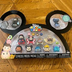 the mickey mouse ear toy is in its box on the floor next to other disney figurines