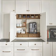 an open cabinet in the middle of a kitchen with coffee maker and other items on it