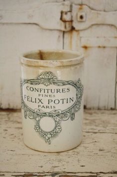 an old fashioned container sitting on top of a wooden table next to a white door