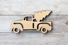 a wooden toy truck with a christmas tree on the back in front of white wood planks