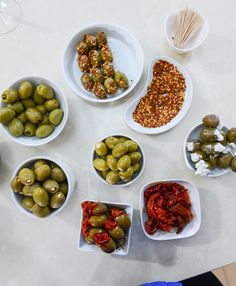 several bowls filled with different types of olives and other foods on top of a table