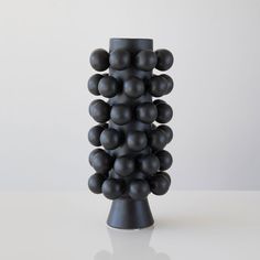 a tall black vase sitting on top of a white table