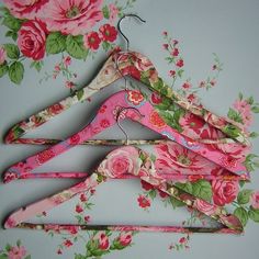 three pink flowered clothes hangers on a blue background with the word pretty written below them