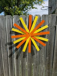 an orange and yellow clock on the side of a wooden fence