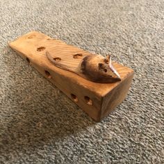 a toy mouse sitting on top of a piece of wood with holes in the middle