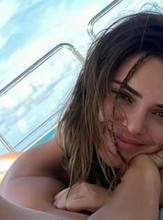 a beautiful young woman laying on top of a bed next to a boat in the ocean