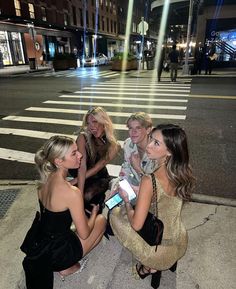 four women sitting on the ground talking to each other in front of a crosswalk