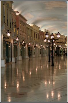 an empty shopping mall with lights on either side of the storefronts and street lamps