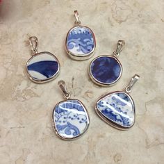 four blue and white pendants sitting on top of a marble counter next to a red vase