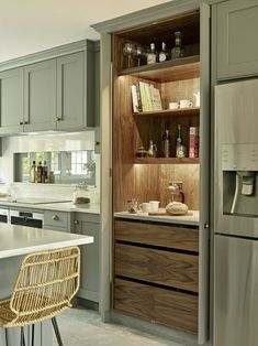 a kitchen with gray cabinets and white counter tops, along with a wicker bar stool