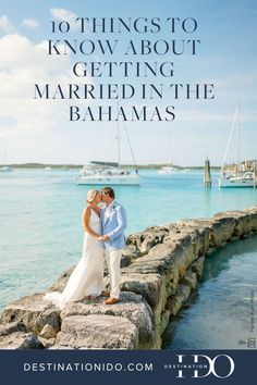 a man and woman standing on the edge of a pier with boats in the background