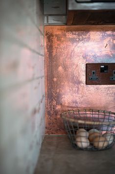 two eggs are in a wire basket on the counter next to an electrical outlet and microwave