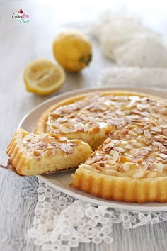 a lemon tart sitting on top of a white plate next to sliced lemons