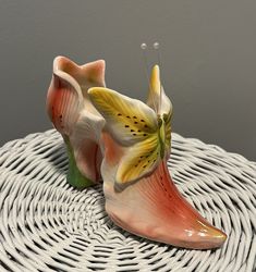 two ceramic shoes sitting on top of a wicker table