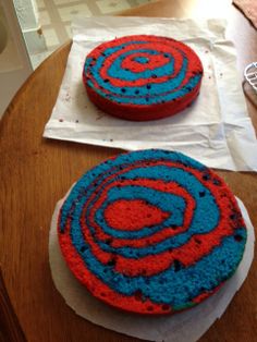 two red and blue cakes sitting on top of a wooden table