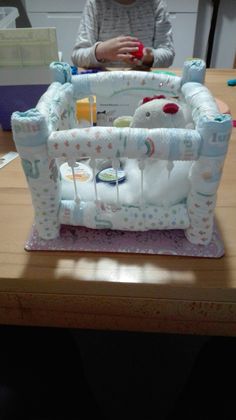 a baby's crib cake sitting on top of a wooden table next to a woman