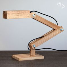 a wooden table lamp with a black cord attached to the arm and one light plugged in