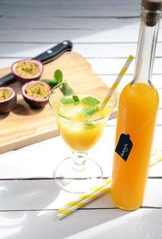 an orange juice in a glass next to a bottle