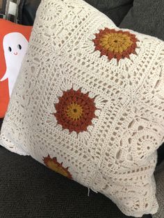 a crocheted pillow sitting on top of a couch next to a stuffed ghost