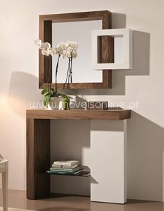 a mirror sitting on top of a wooden shelf next to a vase with flowers in it